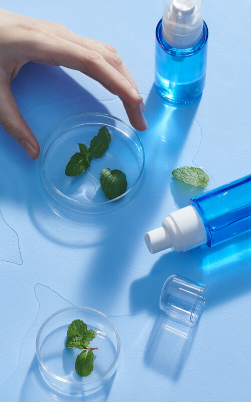 hand with blue vials and petri dishes with leaves