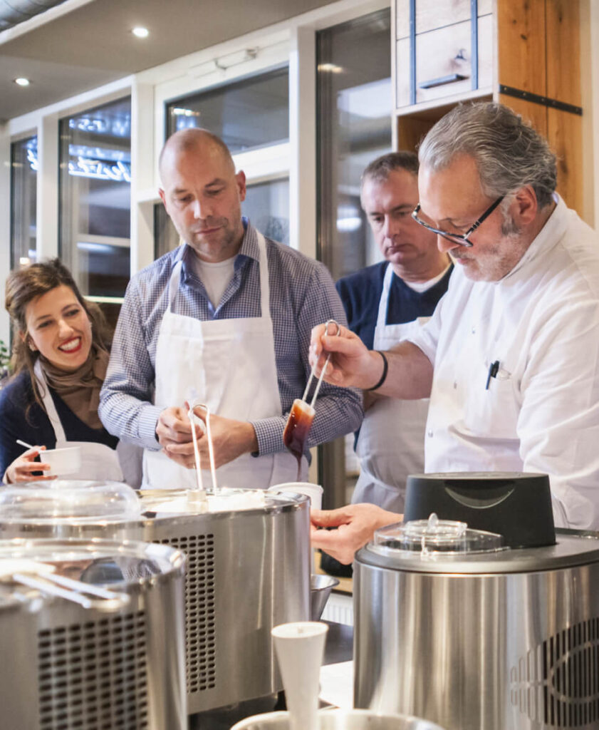 Group of people watching a chef prepare a dessert